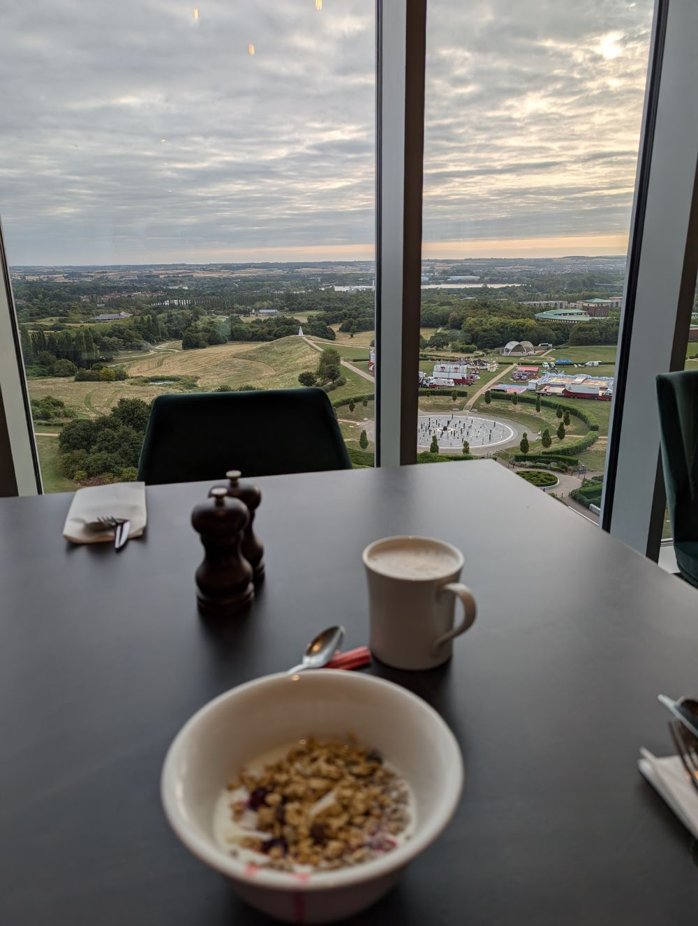 a bowl of cereal and coffee in the foreground and a view out over a park and sunrise