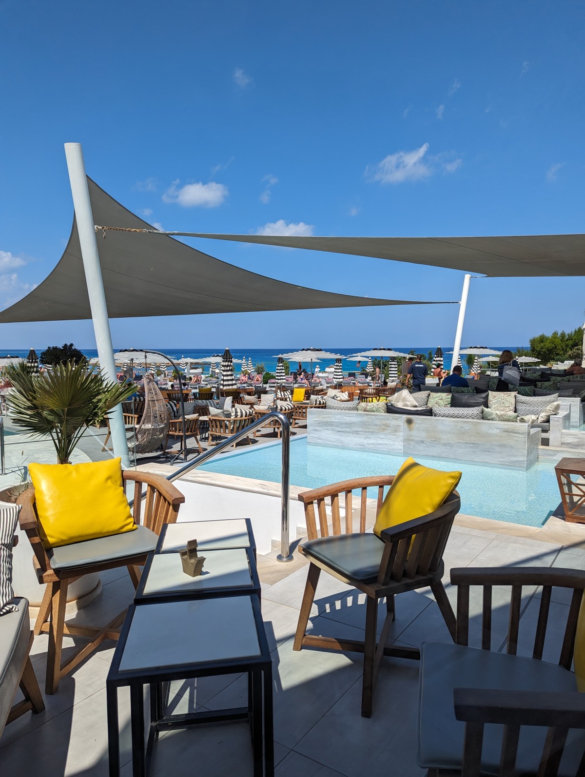 a swimming pool on a fine summer's day with various shades and parasols. The water looks cool and inviting.