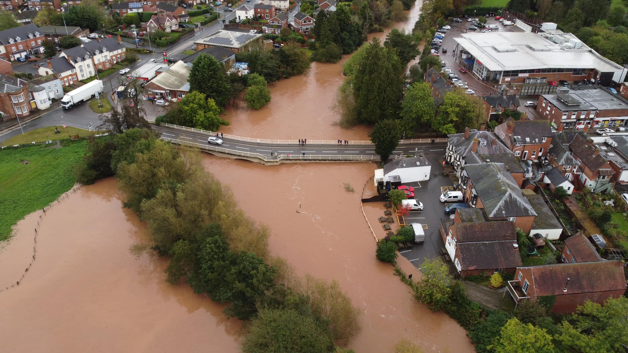 top down view of a town with a swollen river and floodwater invading some houses and gardens