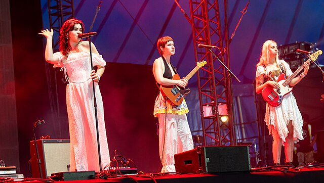 Three women stood on a stage performing music