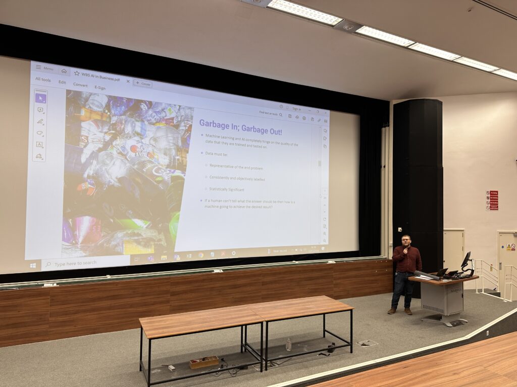 James stood on a stage in front of a podium with slides projected behind him - 